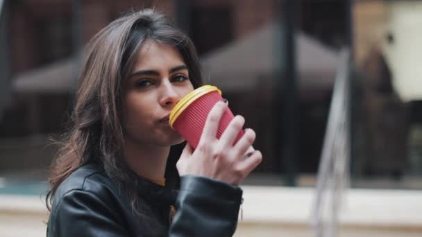 아름 다운 젊은 여자는 매력적인 외모, 귀여운 모양과 도시에서가 자 켓. 카메라를 보며 커피 한잔과 함께 비즈니스 여자의 놀라운 보기 — 비디오