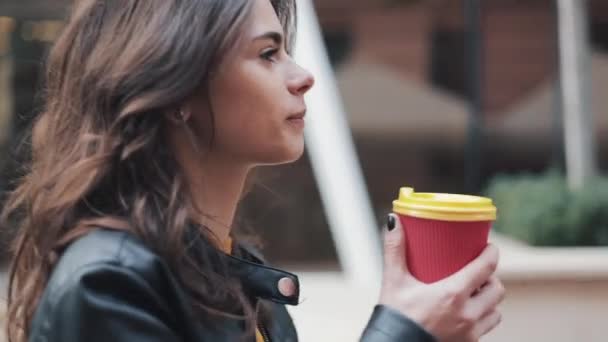 Schöne junge Frau mit attraktivem Aussehen, bezauberndem Look und Herbstjacke in der Stadt. erstaunliche Aussicht auf Geschäftsfrau mit einer Tasse Kaffee zu Fuß die Straße hinunter — Stockvideo
