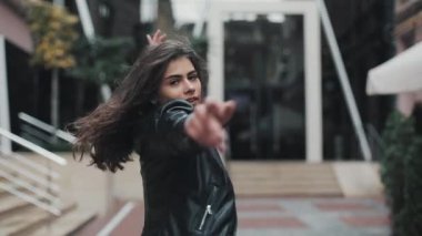Sokakta yürüyen ve dans hareketli mutlu genç kadın. Ağır çekim