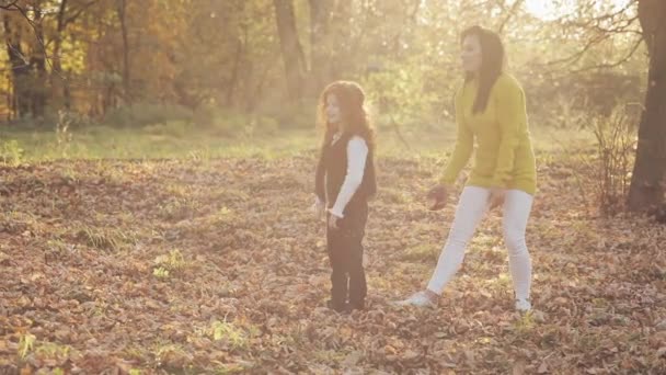 Feliz joven madre y su pequeña hija pelirroja divirtiéndose en un parque de otoño. Juegan y ríen. Movimiento lento — Vídeo de stock