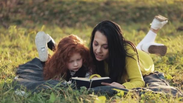 Mãe Bonita Sua Filhinha Fofa Deitada Grama Parque Lendo Livro — Vídeo de Stock