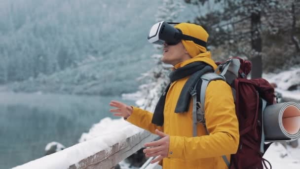 Νεαρός άνδρας ελκυστική στο κίτρινο σακάκι απολαμβάνοντας ακουστικά γυαλιά εικονικής πραγματικότητας ή 3d παιχνίδι σε εξωτερικούς χώρους στο χειμερινό βουνό. Τεχνολογία, καινοτομία, κυβερνοχώρο και τυχερού παιχνιδιού — Αρχείο Βίντεο