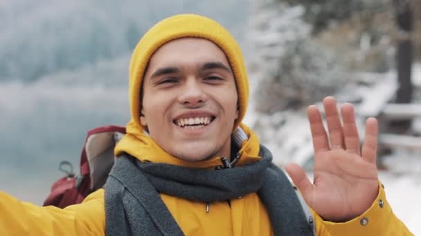 冬休みにビデオ チャットを持つ若い旅行者の男。彼の友人の冬を共有している携帯電話カメラで web カメラに手を振ってハイカー旅行休暇の冒険 — ストック動画