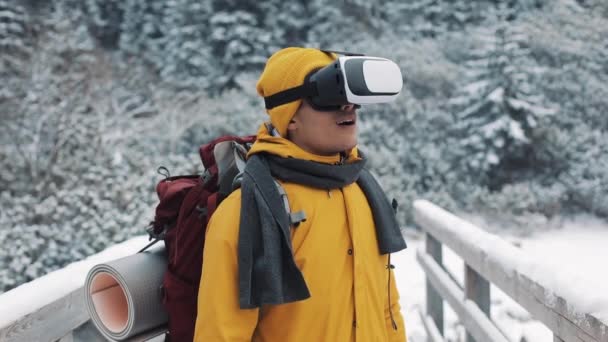 Junger attraktiver Mann in gelber Jacke mit Virtual-Reality-Brille oder 3D-Spiel im Freien in den Winterbergen. Technologie, Innovation, Cyberspace und Gaming — Stockvideo