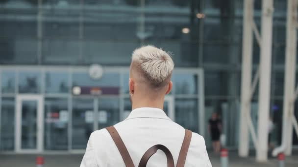 Бізнесмен на роботі. Красивий молодий чоловік у білій сорочці їде в аеропорт з рюкзаком і дивиться на годинник. Подорожі, ділова зустріч, зустріч в аеропорту, концепція відправлення — стокове відео
