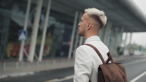 Geschäftsmann am Werk. schöner junger Mann in weißem Hemd auf dem Weg zum Flughafen mit Rucksack und Blick auf die Uhr. Reisen, Geschäftstreffen, Treffen am Flughafen, Abflugkonzept — Stockvideo