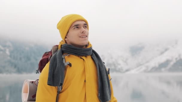 Hombre viajero de pie en las montañas cubiertas de nieve cerca del hermoso lago. Caminante mirando la hermosa naturaleza — Vídeos de Stock