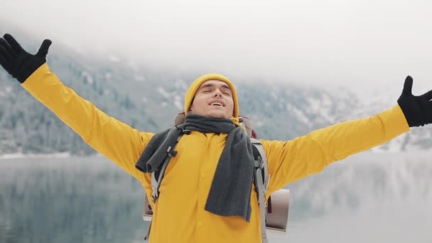 站在山顶上的年轻徒步男子。旅行者举手。成功和赢家的概念。冬季时间 — 图库视频影像