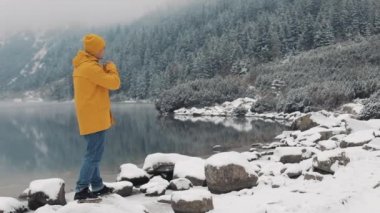 Ellerde, soğuk hava üfleme uzun yürüyüşe çıkan kimse adam. Karlı dağları güzel göl yakınında duran genç yolcusu