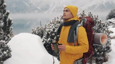 Güzel dağlar kış zamanında. Uzun yürüyüşe çıkan kimse adam sarı kış giysileri giyen sıcak çay veya kahve dışarıda soğukta içiyor. O bir görünüme sahiptir