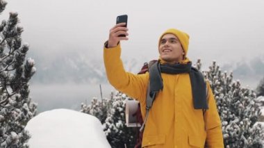 Güzel dağlar kış zamanında. Sarı kış giysileri giyen adam sakallı, al selfie güzel dağ ve dağ gölü arka planı