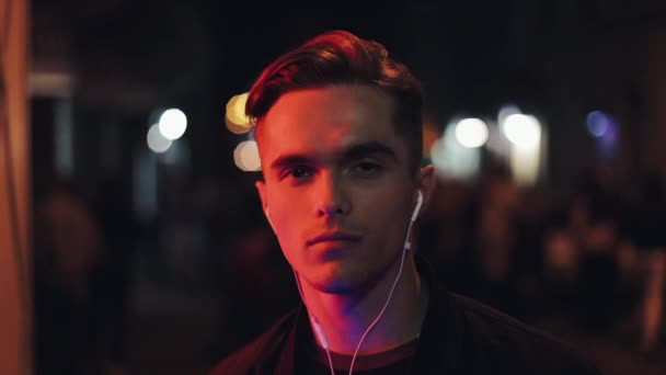 Attraktiver Mann mit Kopfhörern nachts auf der Straße Nahaufnahme Porträt — Stockvideo