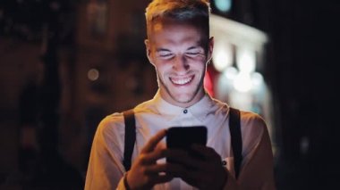 Gece şehir sokakta Smartphone ayakta kullanan genç çekici adam. İletişim, seyahat, turizm, dating, iş kavramı