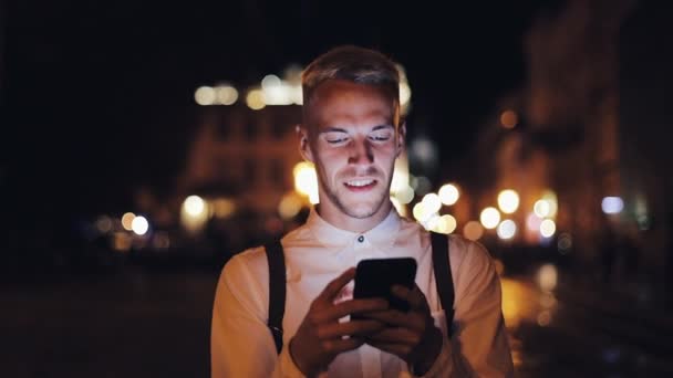 Aantrekkelijke jongeman met smartphone lopen op straat van de stad van de nacht. Communicatie, reizen, toerisme, dating, bedrijfsconcept — Stockvideo