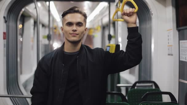 Hombre guapo mirando a la cámara en el tranvía y sonriendo, sosteniendo la barandilla. Steadycam tiro — Vídeo de stock