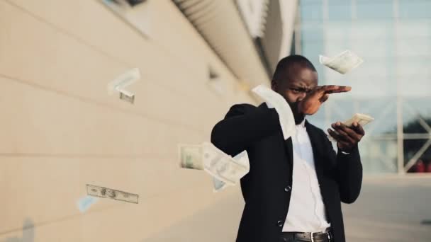 Jonge gelukkig zakenman scatter de dollars en grappige dansen in de straat. Geld regen, dalende dollar. Het is gelegen in de buurt van het office-center, slow-motion. Succesvol bedrijf — Stockvideo