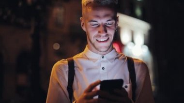 Gece şehir sokakta Smartphone ayakta kullanan genç çekici adam. İletişim, seyahat, turizm, dating, iş kavramı