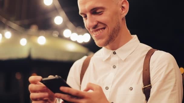 Giovane uomo attraente utilizzando smartphone in piedi sulla strada della città di notte. Comunicazione, viaggi, turismo, incontri, business concept — Video Stock