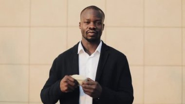 Büyük miktarda para onun elinde tutan mutlu Afrika kökenli Amerikalı iş adamı. Ofis merkezi veya banka yakınlarında sokakta duruyor. İş tarzı, kazanç, para, başarı, kariyer.