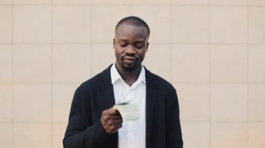 Ayakta paralarını gösterilen çevre ofis dışında Afrikalı-Amerikalı işadamı portresi. İş, insanlar, mali ve kolay para kavramı