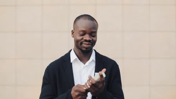 Portrait of African american businessman standing outside near office building showing off their money. Business, people, finances and easy money concept — Stock Video