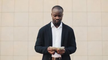 Afrikalı-Amerikalı genç başarılı iş adamı sokakta duran ve para sayma. Başarılı iş, kazançlar, piyango, kolay para kavramı