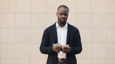Afrikalı-Amerikalı genç başarılı iş adamı sokakta duran ve para sayma. Başarılı iş, kazançlar, piyango, kolay para kavramı