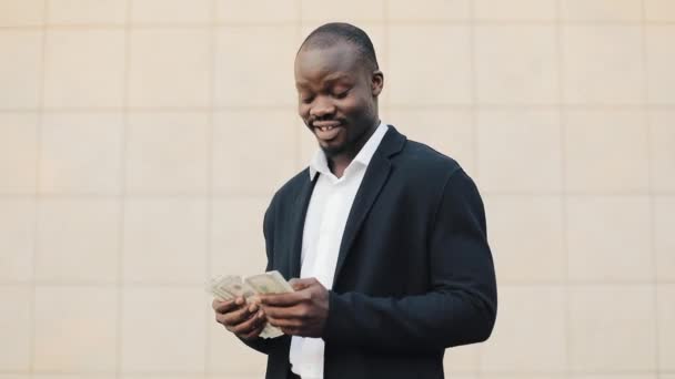 Молодой успешный афроамериканский бизнесмен стоит на улице и считает деньги. Успешный бизнес, выигрыш, лотерея, легкая концепция денег . Видеоклип
