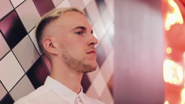 Retrato del joven guapo de pie junto a la pared en el bar nocturno con una cara triste. Primer plano La depresión es un concepto de día difícil — Vídeo de stock