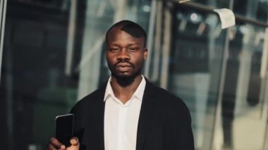 Afrika kökenli Amerikalı işadamı kamera aşağı her yerde uçan para süre bakarak portresi. Smartphone elele. Ağır çekimde işadamı para yağmur