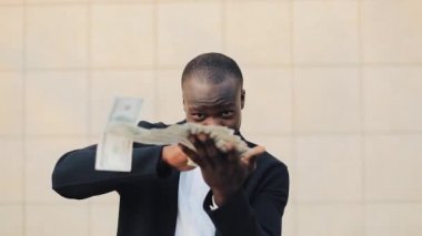 Mutlu, başarılı Afrikalı-Amerikalı işadamı kamera için para atma. Para yağmur, düşen dolar. Ağır çekim. Başarılı iş