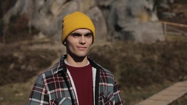 Porträt eines jungen Wanderers, der in den Bergen steht und in die Kamera lächelt. schöne Felsen Hintergrund. im Freien — Stockvideo