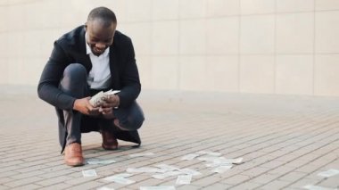 Afrika kökenli Amerikalı işadamı hızlı bir şekilde sokakta dağınık para toplar. Para yağmur. İnsan açgözlülük. İş, insan ve finans ve para kaybı kavramı