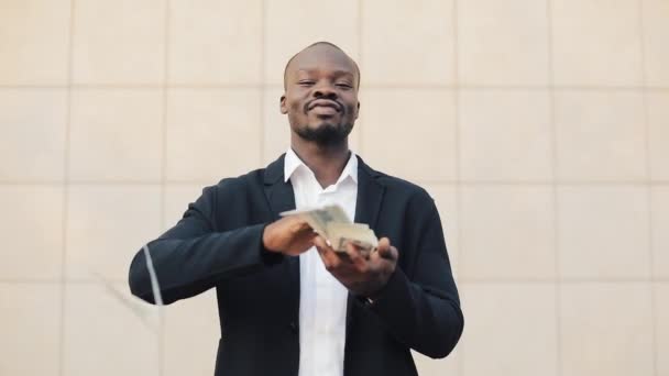 Счастливый, успешный африканский бизнесмен бросает деньги на камеру. Деньги, падающие доллары. Медленное движение. Успешный бизнес — стоковое видео