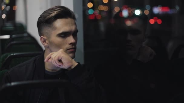 Sad unhappy man riding tram through the city at night. Depressed look of a young man in empty transport — Stock Video