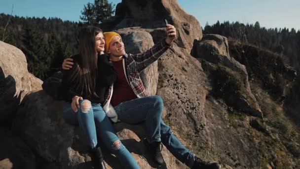 愛の若いカップルは、岩の上に座っているし、selfie の肖像画を取る。男と女の有名な観光名所を訪問 — ストック動画