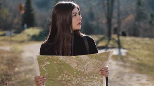 Ung vacker kvinna vandring på en skogsstig, stoppar och kontrollerar karta för vägbeskrivning. Kvinna med gammal karta i bergen — Stockvideo