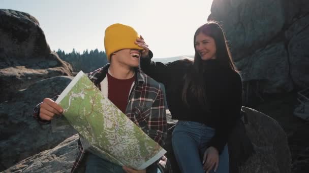 Reise in die Berge. schönes verliebtes Paar sitzt auf einem Felsen und lernt eine Landkarte. Sie reden miteinander, lachen und haben Spaß — Stockvideo