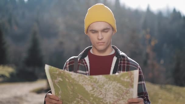 Travelling to the mountains. Hiker man holds old map standing in the forest and looking around. The tourist travels in beautiful mountains. — Stock Footage Travelling Mountains Hiker Man Holds Old Map Standing Forest Looking Royalty Free Stock Video