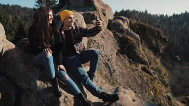 Aşık genç çift kaya ve arkadaşlarınızla video sohbeti yapma oturur. Turizm, iletişim, dinlenme, kavram sohbet.