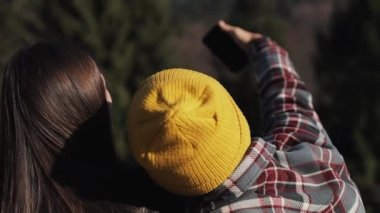 Genç aşk oturur yüksek dağda bir kayanın üzerinde çift ve selfie telefonda yapmak. Ağır çekim