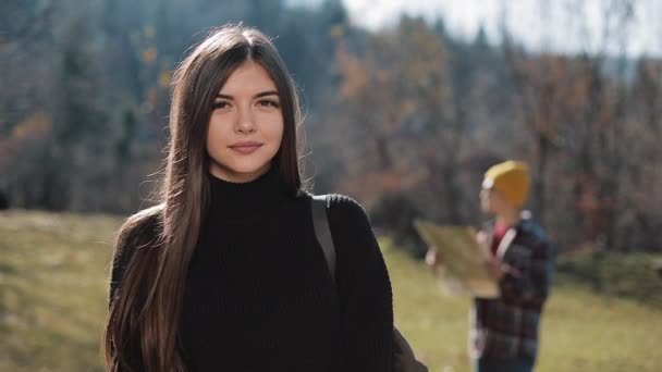 Porträt einer jungen attraktiven Frau, die in den Bergen in die Kamera blickt. Tourist mit Landkarte im Hintergrund — Stockvideo