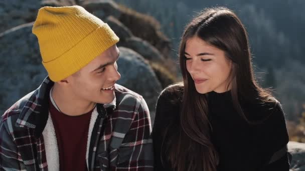 Pasangan pejalan kaki duduk bersama di batu di pegunungan yang indah. Mereka berbicara satu sama lain, tertawa dan bersenang-senang — Stok Video