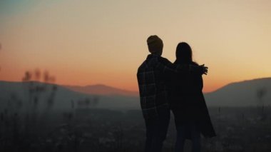 Dağların üzerinden bir gün batımı zevk aşık genç çift silüeti. Tatil, seyahat, aşk, evlilik teklifi kavramı