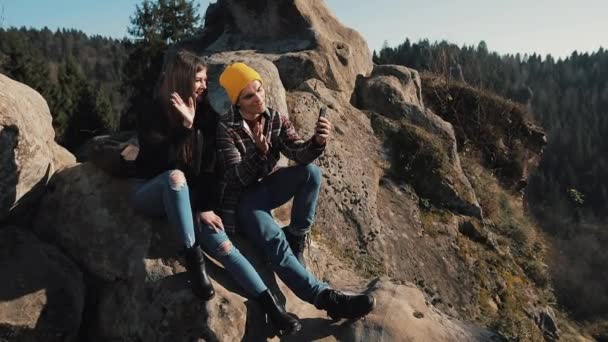 Pasangan muda jatuh cinta duduk di atas batu dan membuat video chatting dengan teman-teman. Pariwisata, komunikasi, istirahat, konsep chatting — Stok Video