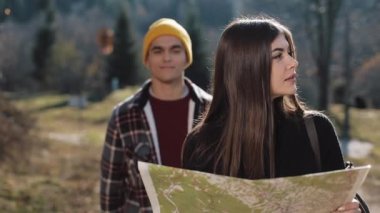 Mutlu çift ayakta dağlarda gülümseyen genç. Onlar onların yürüyüş zevk almak. Turistik harita üzerinde seyir. Yön bulmaya çalışıyorum. Ağır çekim