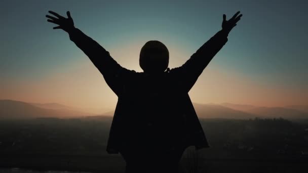 Silueta člověka vyvolává ruce vzhůru stojící na hoře na západ slunce. Koncept svobody — Stock video