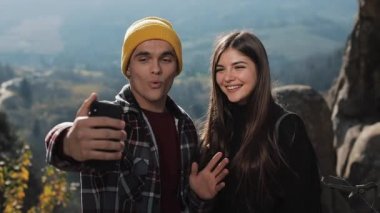 Aşık genç çift yüksek dağ ve arkadaşlarınızla video sohbeti yapma bir kayanın üzerinde duruyor. Turizm, iletişim, dinlenme, kavram sohbet