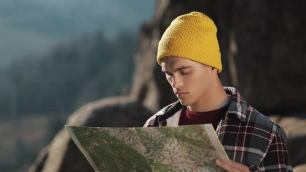 Ταξιδεύοντας στα βουνά. Πεζοπόρος άνθρωπος κρατά παλιό χάρτη στέκεται στην κορυφή του βράχου. Ο τουρίστας ταξιδεύει στα πανέμορφα βουνά — Αρχείο Βίντεο
