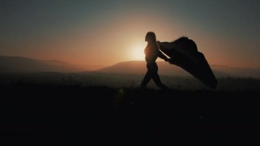 Onun elinde bir pareo ile dağlarda çalışan güzel bir genç kadın silüeti. Ağır çekim. Özgürlük, kolaylığı, başarı, geri kalan kavramı. Günbatımı
